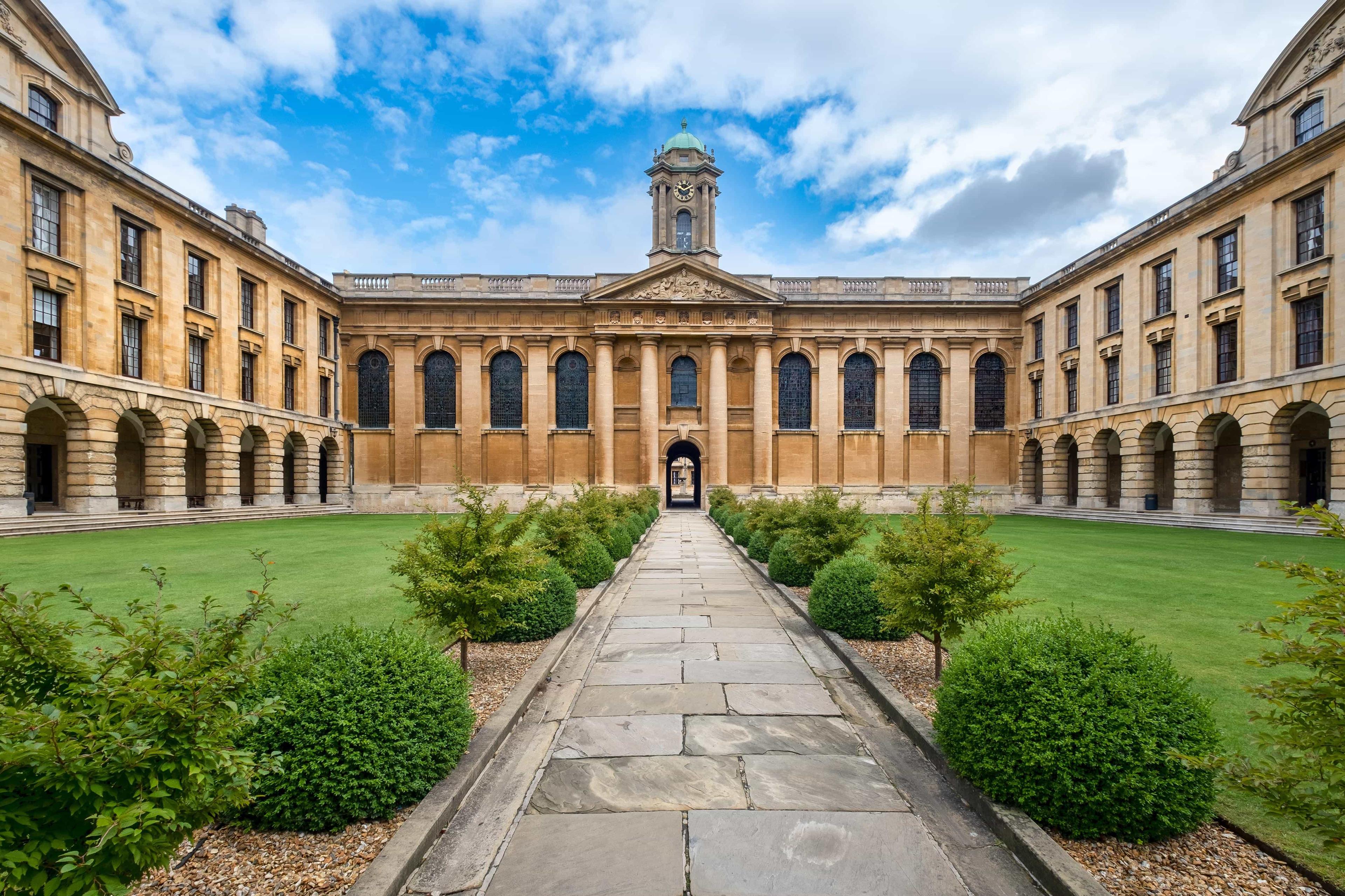 A walkway divides green grass inside the old University of Cambridge court yard.