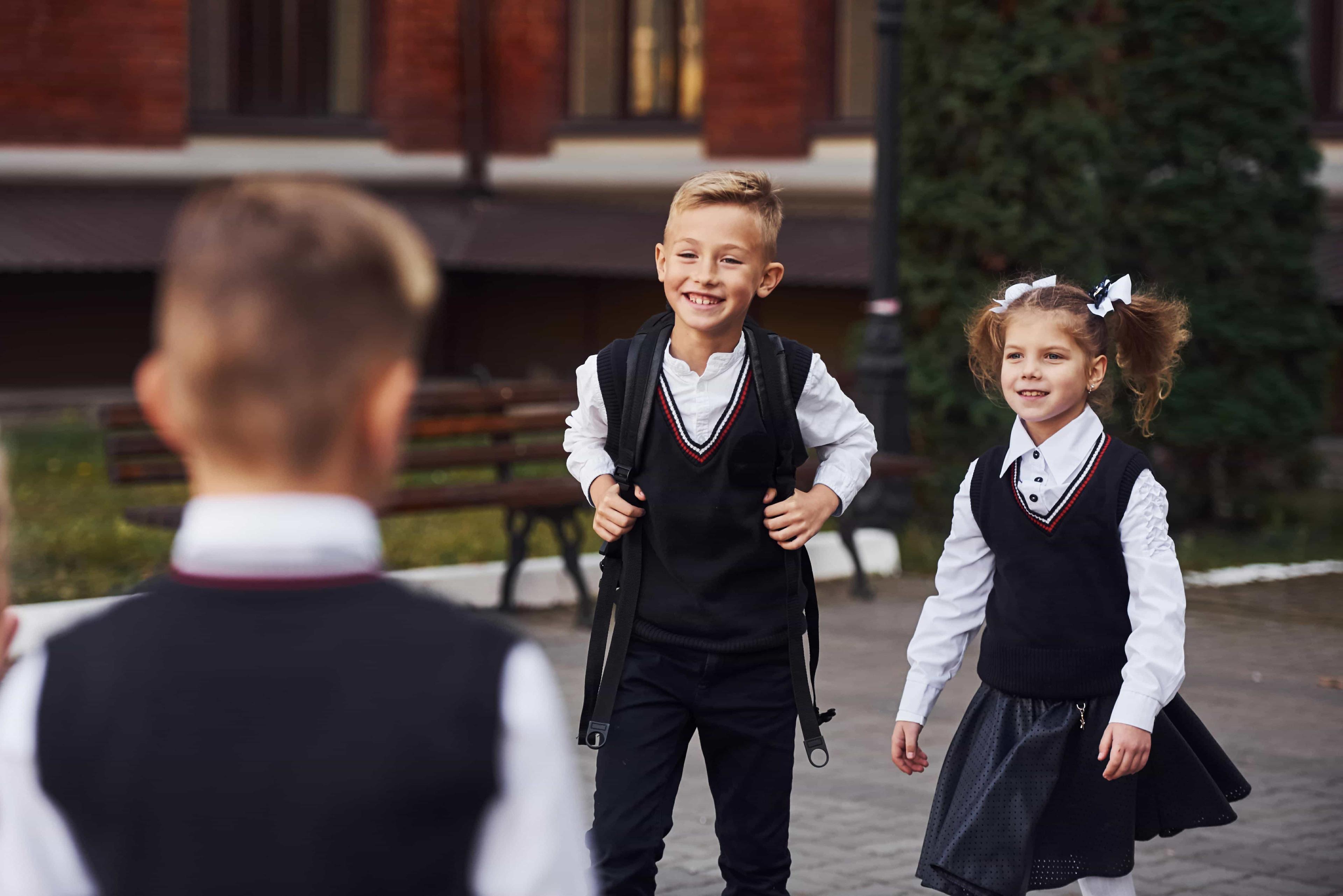 A young boy and girl, carrying backpacks, walk together heading to their school entrance examination.