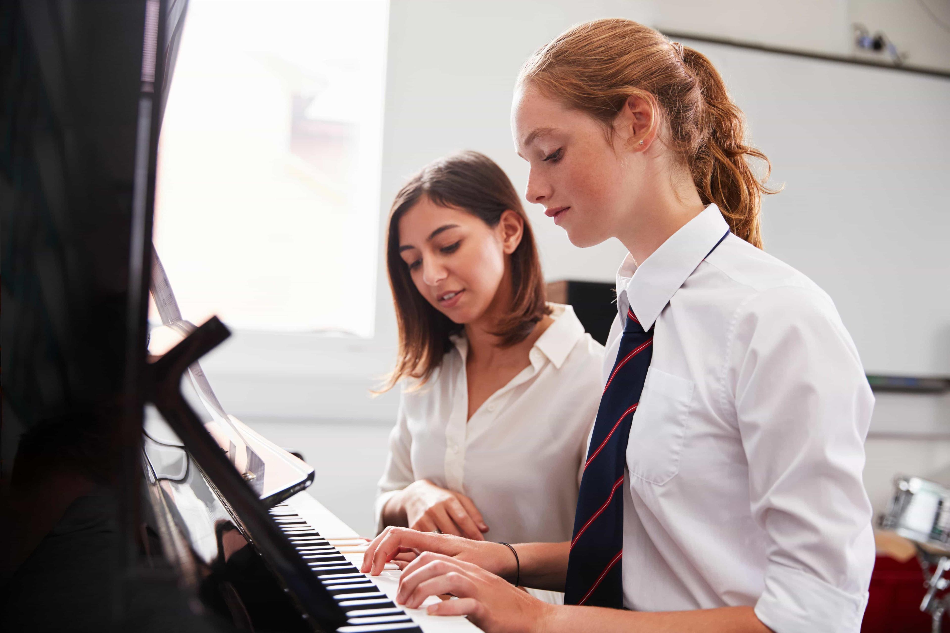 A music tutor demonstrates piano playing techniques to the music scholarhsip at an independent school.