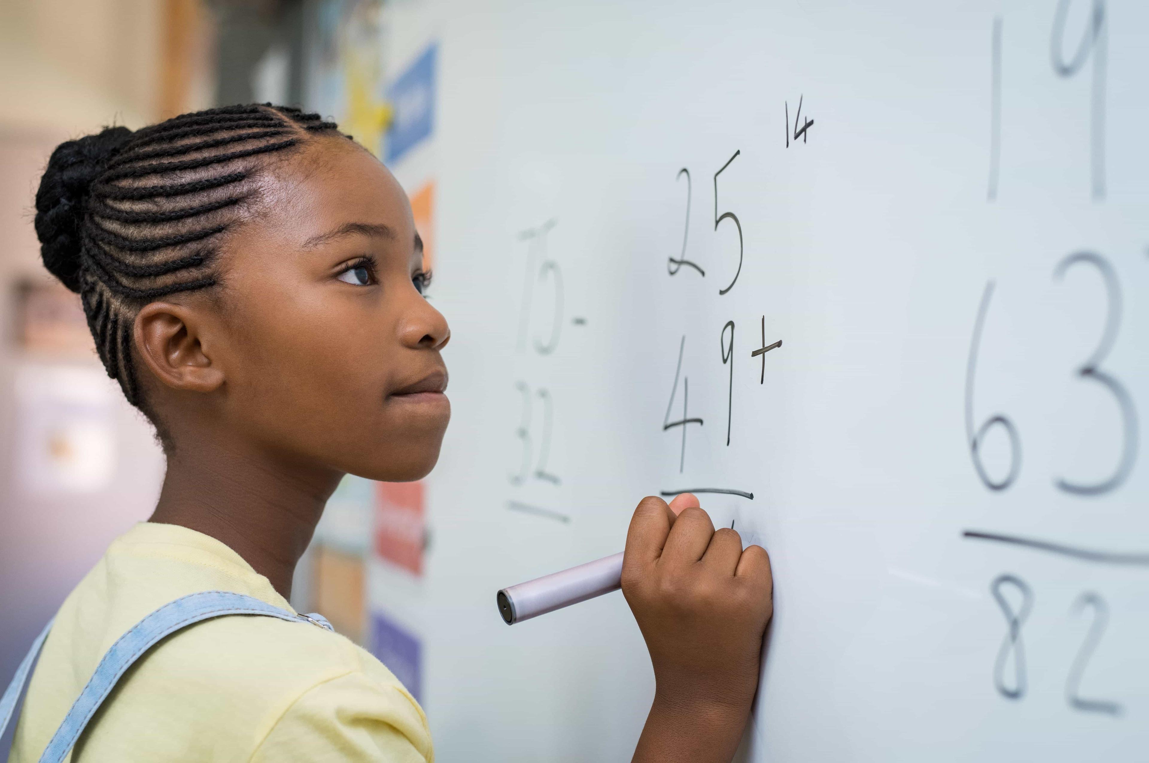 A student works at the whiteboard to solve challenging IB Maths equations for revision.