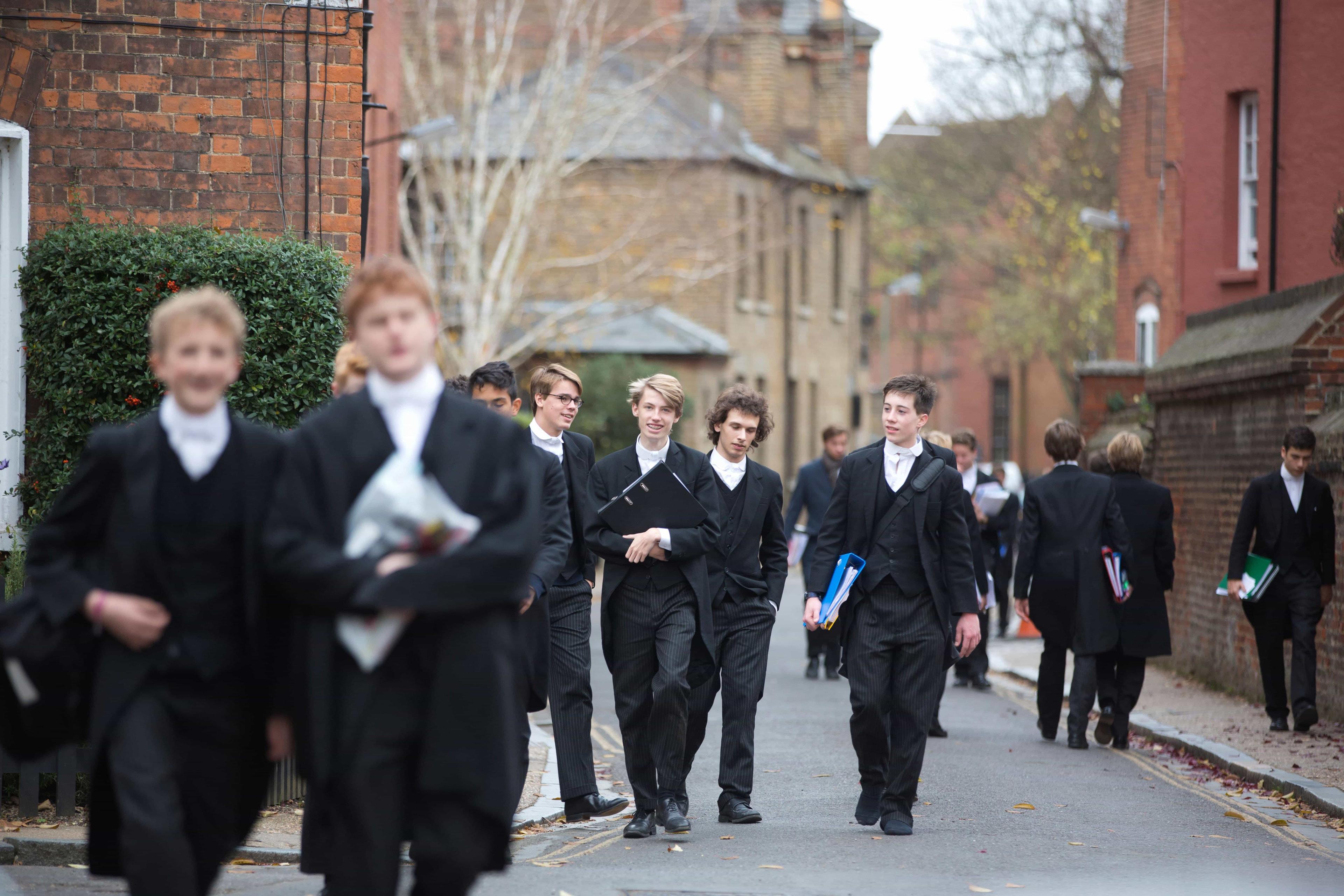 A group of independent school students at Eton College wandering to lessons, talking amogst themselves.