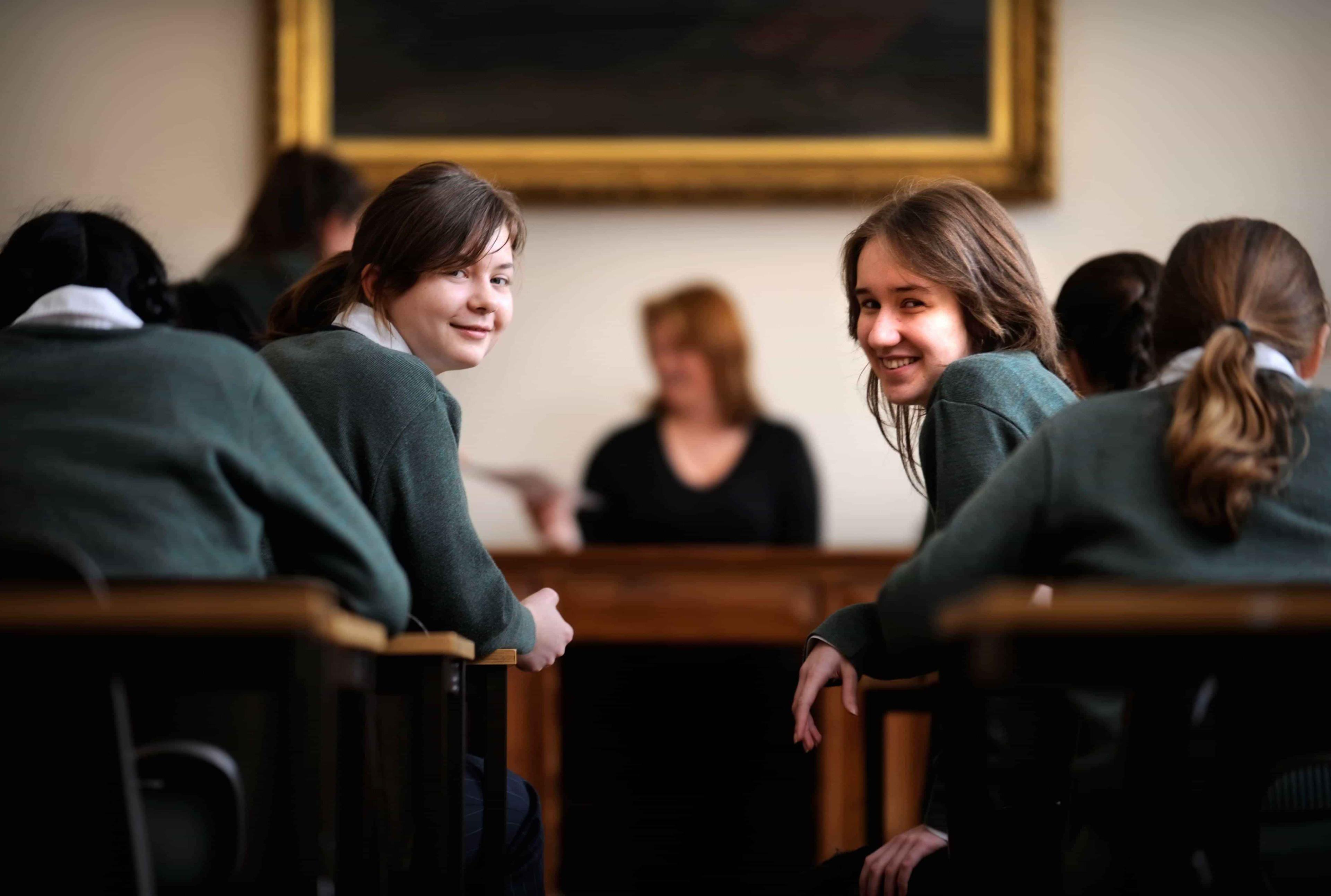 Two students in a Maths lesson look towards the back of the classroom at their tutor.